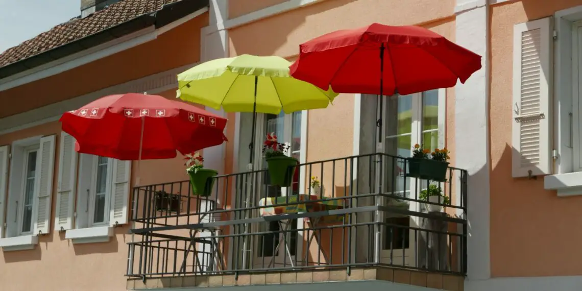 A balcony with red and yellow umbrellas under the clear sky